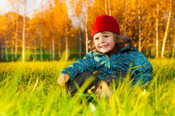 Chlapec sedí v podzimním parku — Stock fotografie