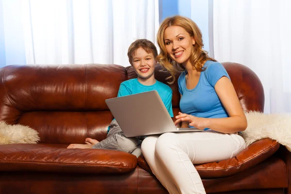 Boy with mum holding laptop on the sofa — Stock Photo, Image