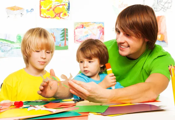 Papà e i suoi bambini tagliano e incollano i mestieri dalla carta — Foto Stock