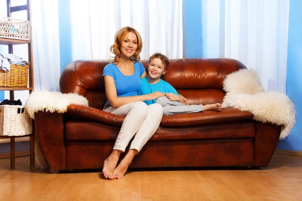 Mother and her child sitting on leather couch — Stock Photo, Image