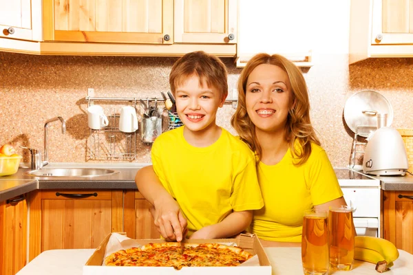 Boy and happy mother slicing pizza — Stock Photo, Image