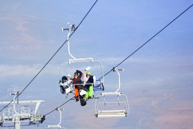 Teleferik üzerinde üç snowboard düşkünleri