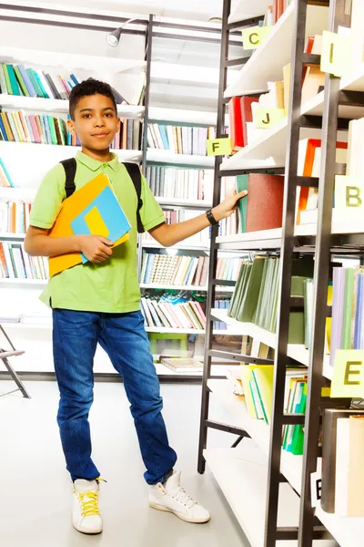 Menino com livros na biblioteca — Fotografia de Stock