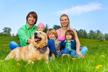 mutlu bir aile ile köpek yeşil çimenlerin üzerinde oturan