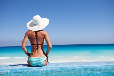Silhouette of young woman on beach with hat clipart
