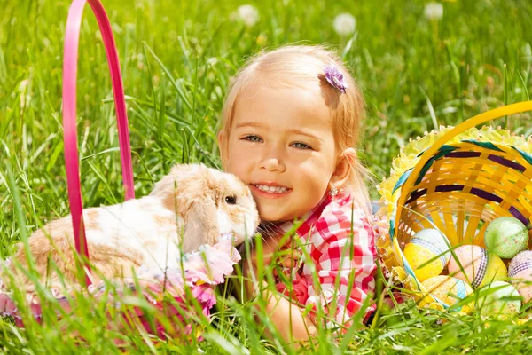 Cute small girl cuddling rabbit in field — Stock Photo, Image