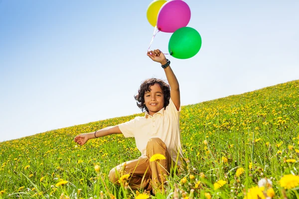 Positiva pojke med flygande ballonger i sommar — Stockfoto