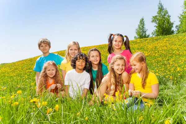 Niños divertidos sentados juntos sobre hierba verde —  Fotos de Stock
