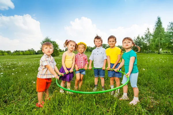 Sechs lustige Kinder halten einen Reifen zusammen — Stockfoto