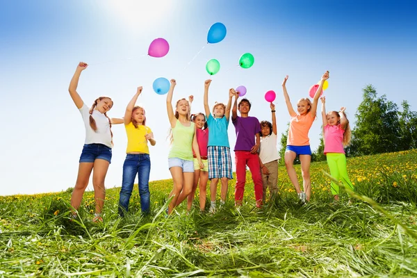 Jumping kids with flying balloons in summer — Stock Photo, Image