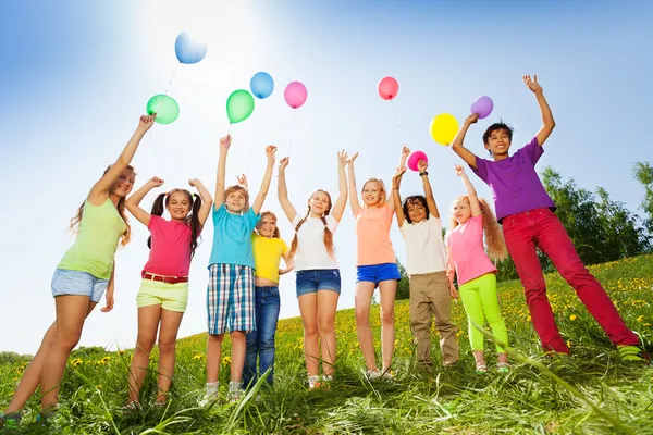 Barn som står med armarna upp till flygande ballonger — Stockfoto