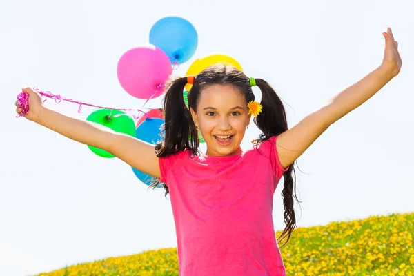 Positiv tjej med armarna upp och ballonger i luften — Stockfoto