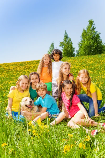 Crianças felizes com cão juntos no prado — Fotografia de Stock