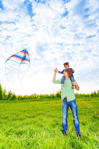 Glimlachend vader houdt van jong geitje en horloges kite in lucht — Stockfoto