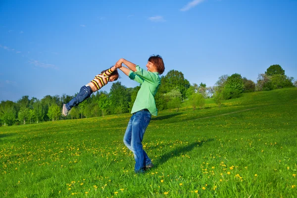 Father holds kid in the air while swirling him — Stock Photo, Image