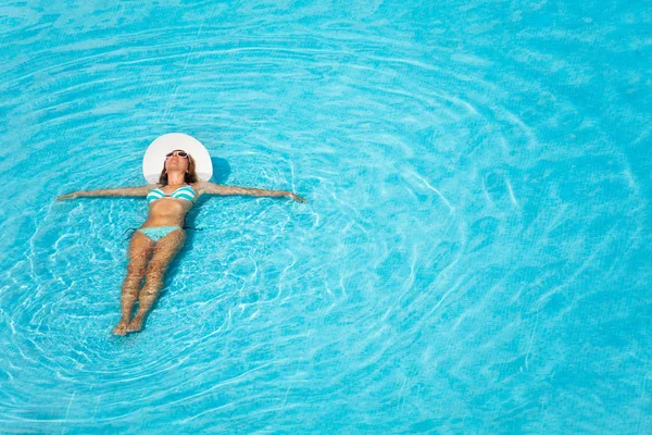Menina com chapéu nadando na piscina cristalina — Fotografia de Stock