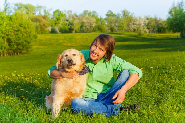 Sorrindo pai com cão sentado no chão no parque — Fotografia de Stock