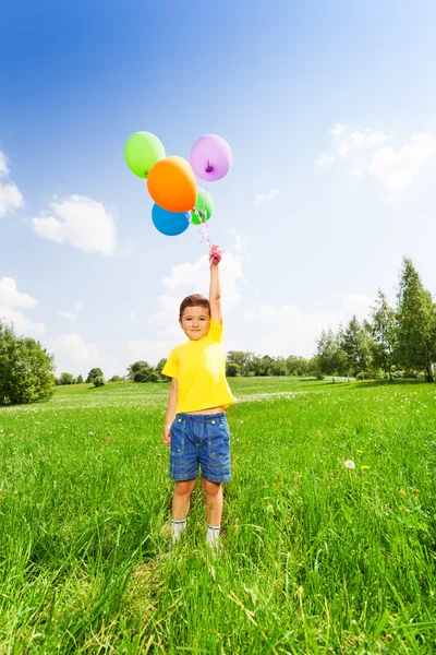 Chłopiec w żółty t-shirt stojący z balonów — Zdjęcie stockowe