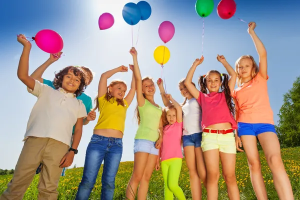 Los niños se paran en media ronda con brazos hasta globos —  Fotos de Stock