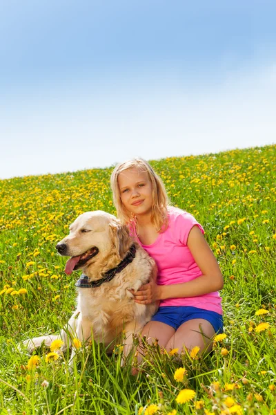 Sorrindo menina abraçando cão sentado na grama — Fotografia de Stock