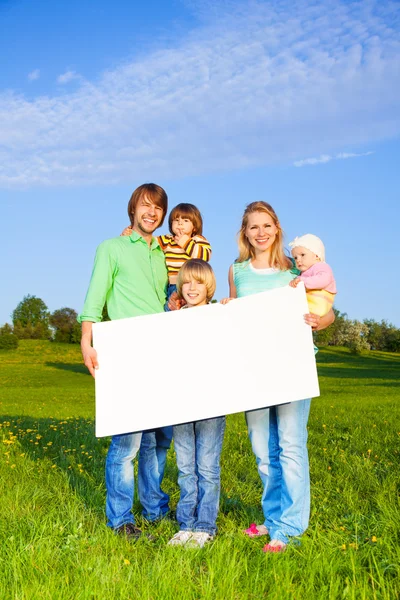 Usmívající se rodina drží bílý čtverec papíru formátu — Stock fotografie