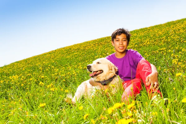 Chlapec objímání, pes sedí na zelené trávě v létě — Stock fotografie