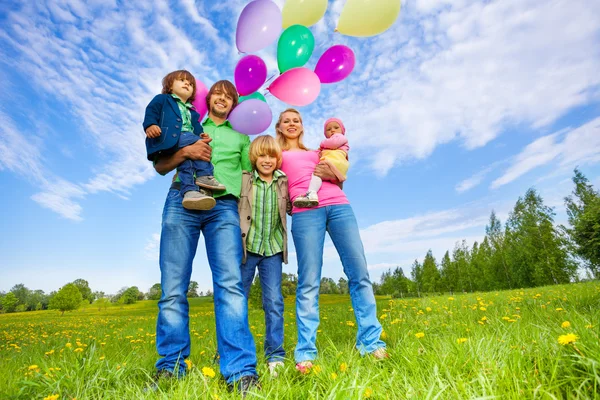 Família feliz fica com balões no parque — Fotografia de Stock