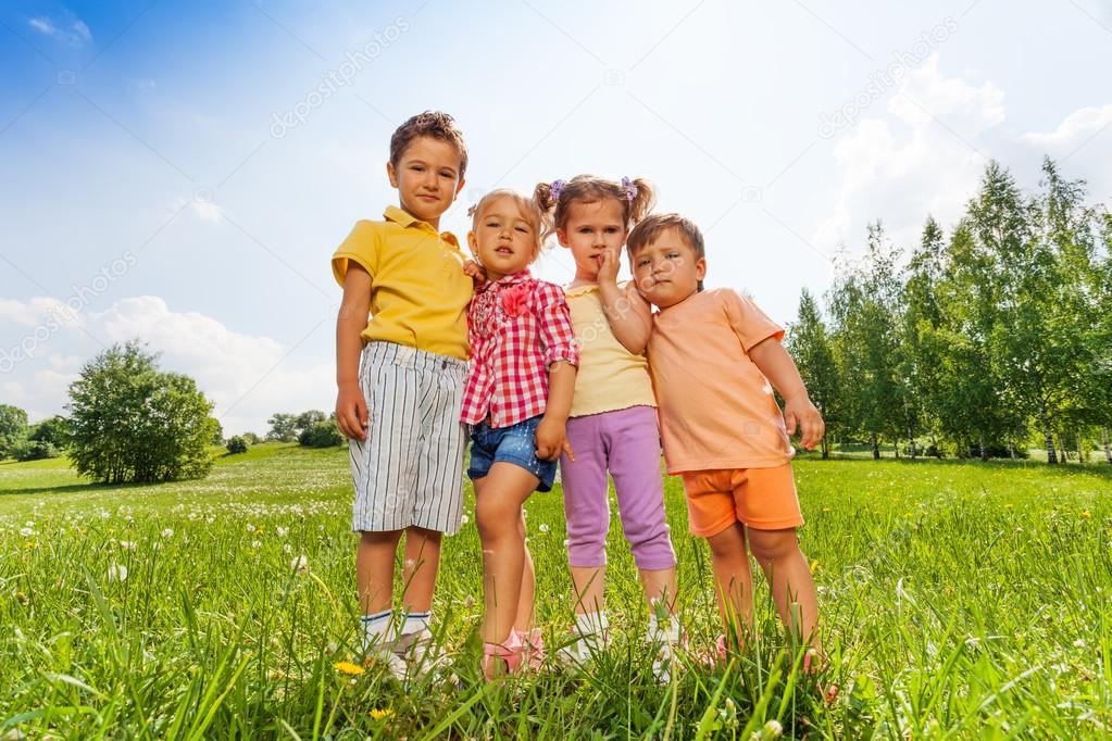 Four kids standing close to each other in meadow