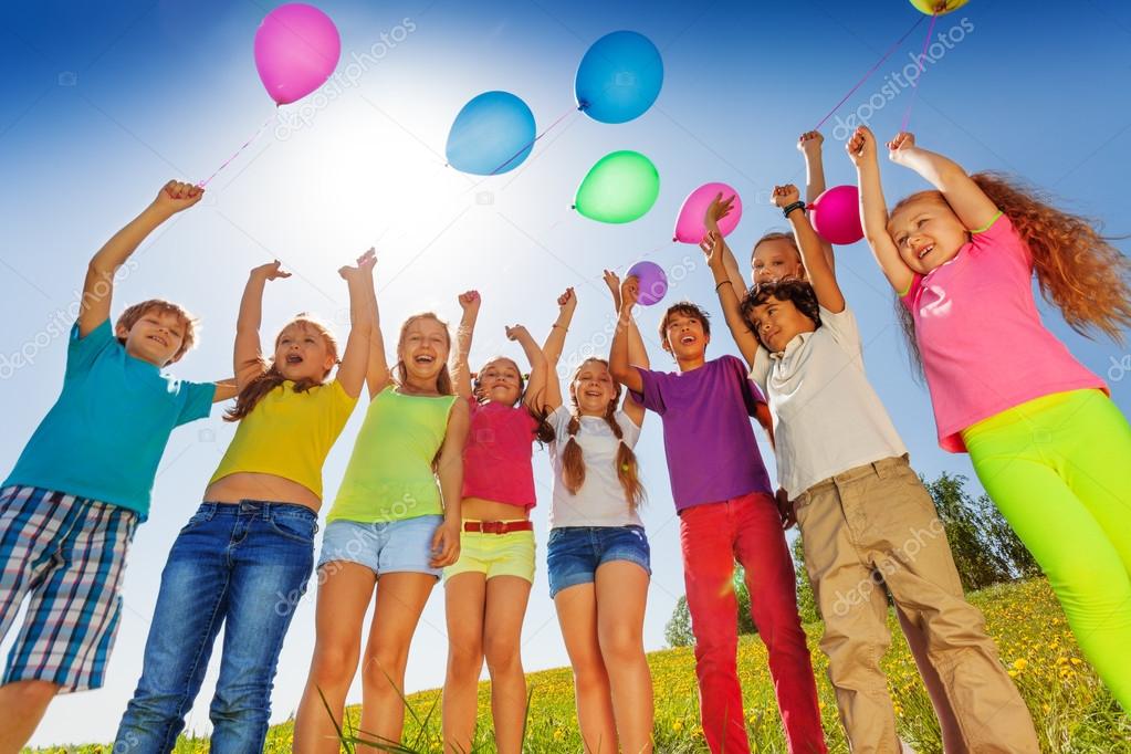 Children stand in semi-circle with balloons up