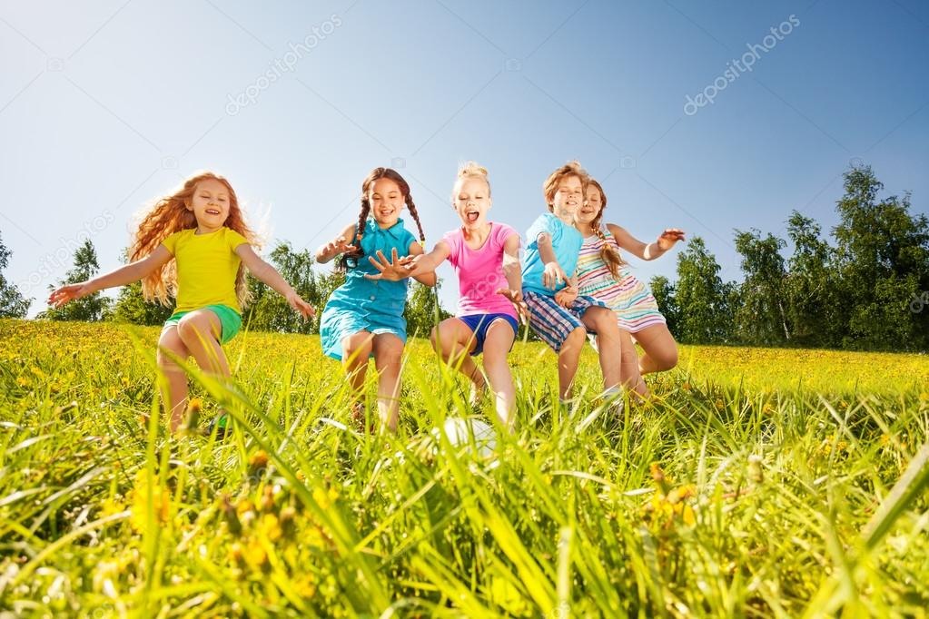 Happy children playing football in yellow meadow
