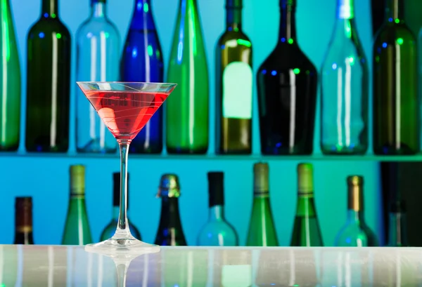 Glas met roze vloeistof staat op tafel van bar — Stockfoto