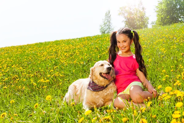 Gelukkig meisje knuffelen hond zittend op het gras — Stockfoto