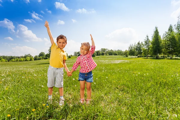 Niño y niña tomados de la mano con la segunda mano hacia arriba —  Fotos de Stock