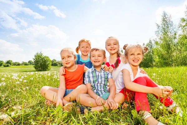 Kinderen zitten op een gras — Stockfoto