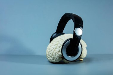 Müzik dinleyen beyin - kulaklıklar mavi arkaplanda yan yana.
