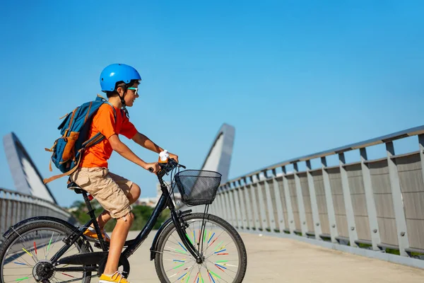 バックパック付きの学校や青いヘルメットから市内自転車に乗る子供の肖像画 — ストック写真