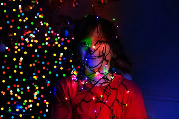 Ritratto Ragazzo Con Ghirlanda Illuminata Sul Volto Vicino Albero Natale — Foto Stock