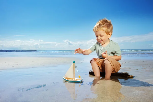 Mały Chłopiec Bawić Się Zabawką Żaglowiec Wiosło Siedzi Plaży Pobliżu — Zdjęcie stockowe