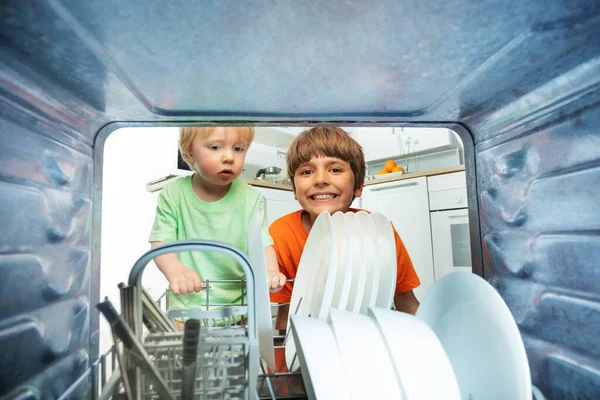 台所で2人の幸せな笑顔の兄弟ヘルパー食器洗い機をアンロード — ストック写真