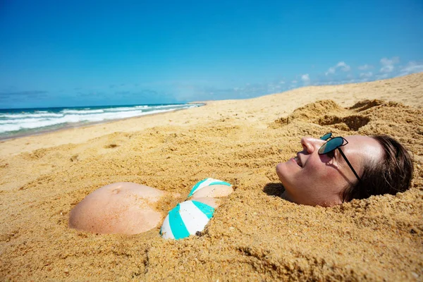 海のビーチで砂の中に埋葬された妊婦の腹と肖像画はサングラスを着用し 横からの笑顔ビュー — ストック写真