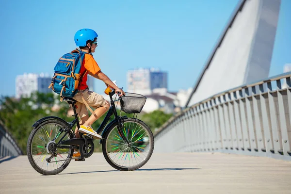 子供の側の景色少年は自転車に乗って街の自転車レーン橋の上に建物を背景にしています — ストック写真