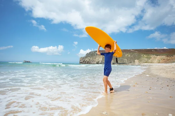 Bonito Menino Ficar Segurando Prancha Surf Laranja Sobre Cabeça Ondas — Fotografia de Stock