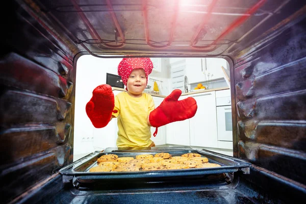幸せな小さなブロンド男の子とともにオーブンからクッキートレイを取ります 内部からの眺め — ストック写真