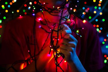 Yılbaşı ağacının yakınındaki ışıklı çelenk ışıklarıyla çocuğun ellerini kapatın.