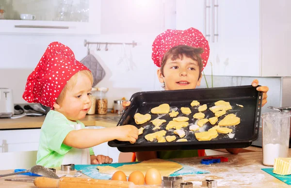 2人の男の子がクッキーを皿の上に置きますキッチンで作る形はベーキングの準備 — ストック写真