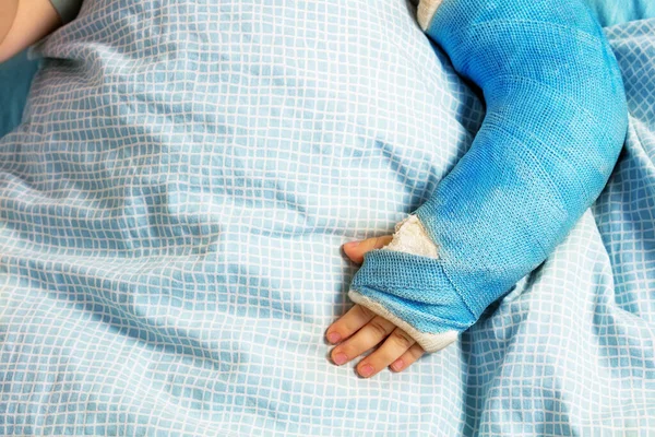 Little boy\'s broken hand in a plaster cast lay in hospital bed