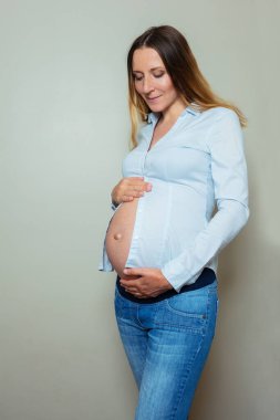 Hamile çalışan kadın göbeğini gösteren resmi bir gömlek giyer.