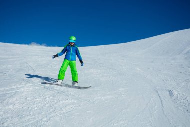 Snowboard yapan çocuğun dağ yamacından aşağı inişi.