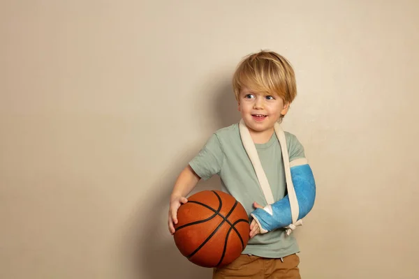 Smiling Positive Little Blond Boy Broken Hand Cast Holding Basketball — Stockfoto