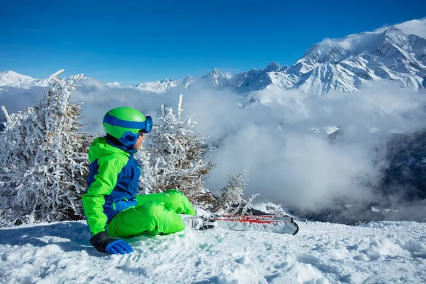 Mały Chłopiec Alpejskimi Narciarzami Siedzi Śniegu Obserwując Górę Nad Szczytami — Zdjęcie stockowe